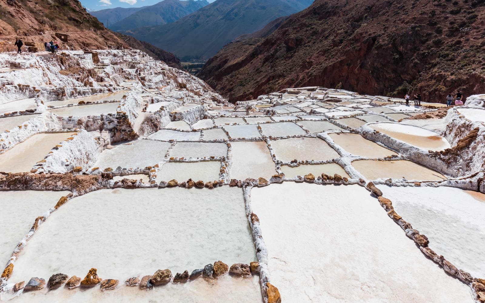 The white salt terraces of Salineras de Maras stepping down a red valley